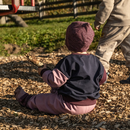Kind trägt den leichten Sweater aus Bio-Baumwolle, sowie die Baby Hose und die Mütze von Tuchwerk, bequem geschnitten für Bewegungsfreiheit und Komfort.